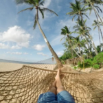 retiring in Panama pros and cons Man laying on hammock on beach with palm trees