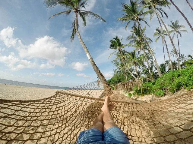 retiring in Panama pros and cons Man laying on hammock on beach with palm trees